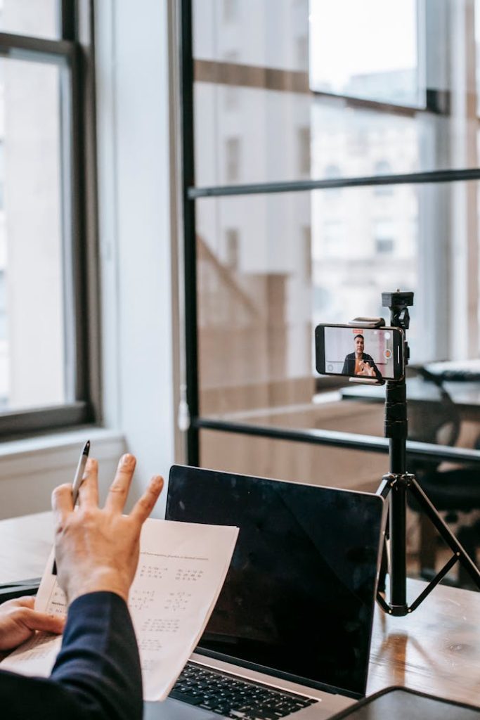 A person conducting an online education session using a laptop and smartphone.
